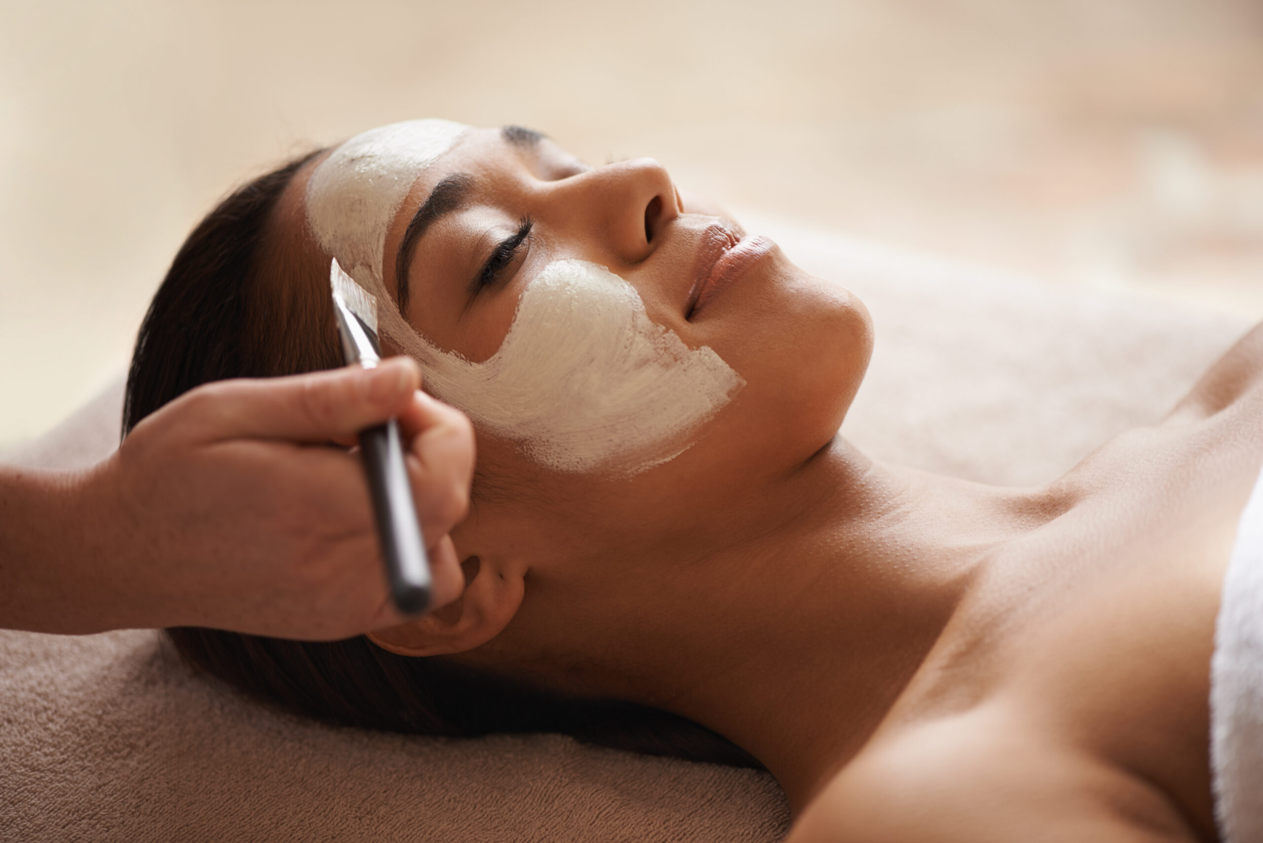 Facial mask being applied to woman during professional skincare treatment