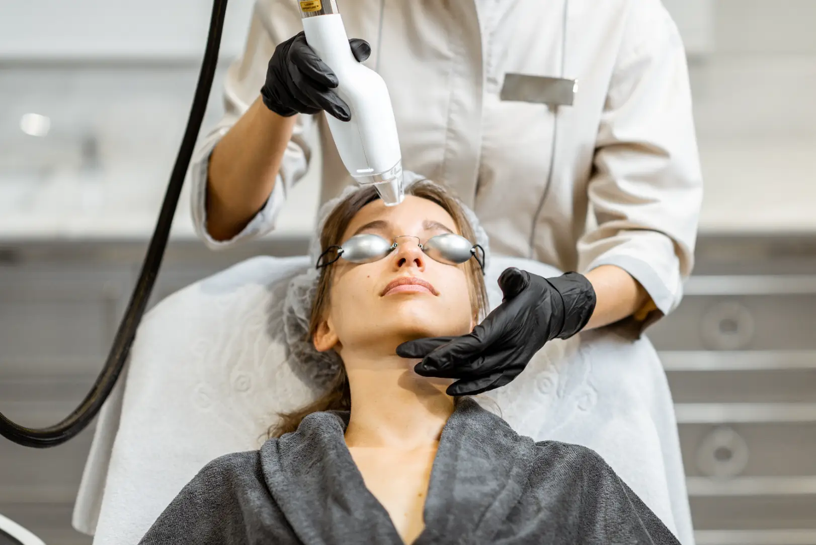 Practitioner performing a laser skin treatment on a patient wearing protective eyewear.