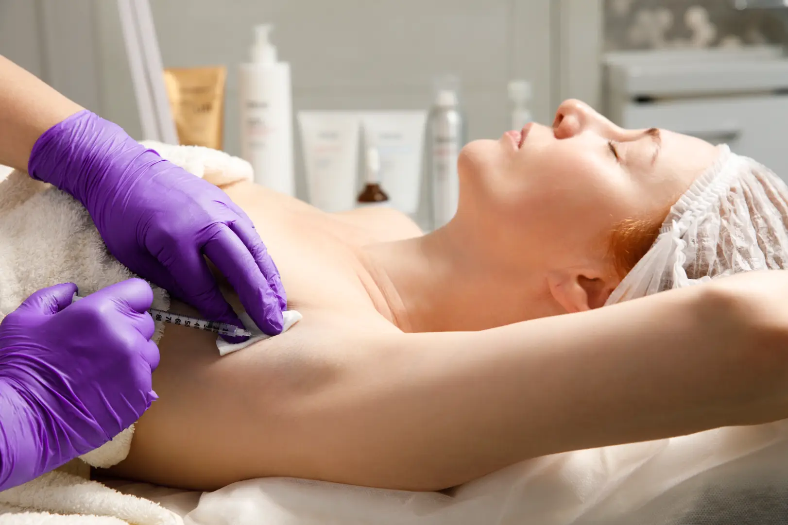 Practitioner administering an injection to the underarm during a treatment session.
